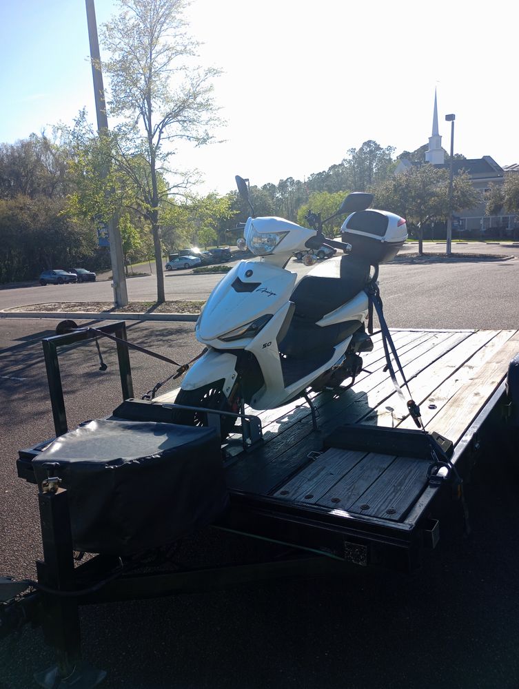 Motor scooter strapped down for transport on a flatbed trailer